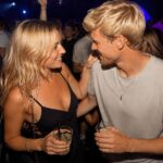 Mann und Frau tanzen in der Disco mit Blickkontakt und Getränken als Beispiel für Körpersprache beim Flirten