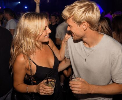 Mann und Frau tanzen in der Disco mit Blickkontakt und Getränken als Beispiel für Körpersprache beim Flirten