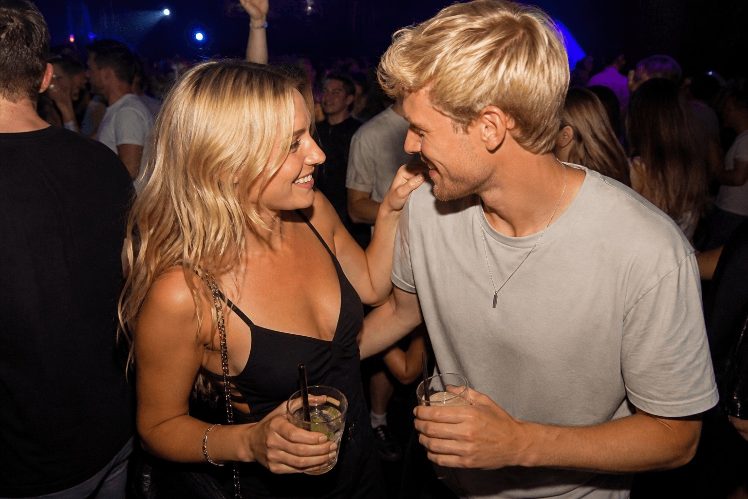 Mann und Frau tanzen in der Disco mit Blickkontakt und Getränken als Beispiel für Körpersprache beim Flirten