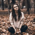 Frau sitzt nachdenklich im Park und reflektiert Probleme bei der Partnersuche und Beziehungen