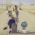 Frau auf Singlereise sitzt mit Karte auf einer Straße und plant alleine ihren Urlaub